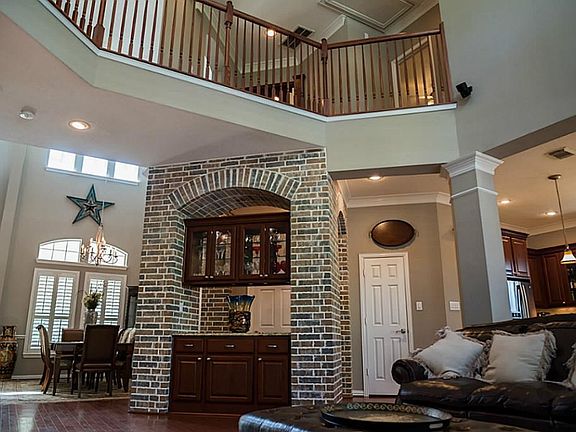 Shown is the dramatic dry bar with seed glass front upper cabinets, granite counter and gorgeous brick work.  This bar is open to the dining room and the living room. Notice the two story ceilings and the openness of the space.