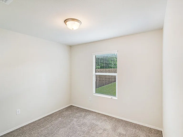 Neutral tone walls with a single window featuring horizontal blinds