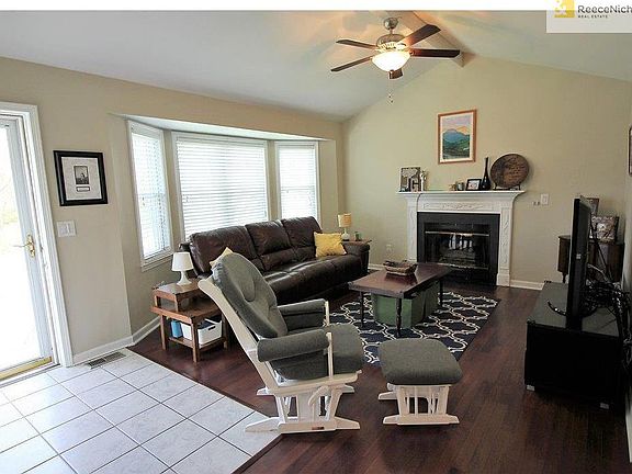 Spacious living room features a bay window, vaulted ceilings, cozy fireplace, and hardwood floors.