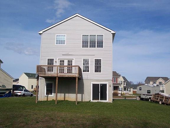 Back of home with deck and entry into Basement