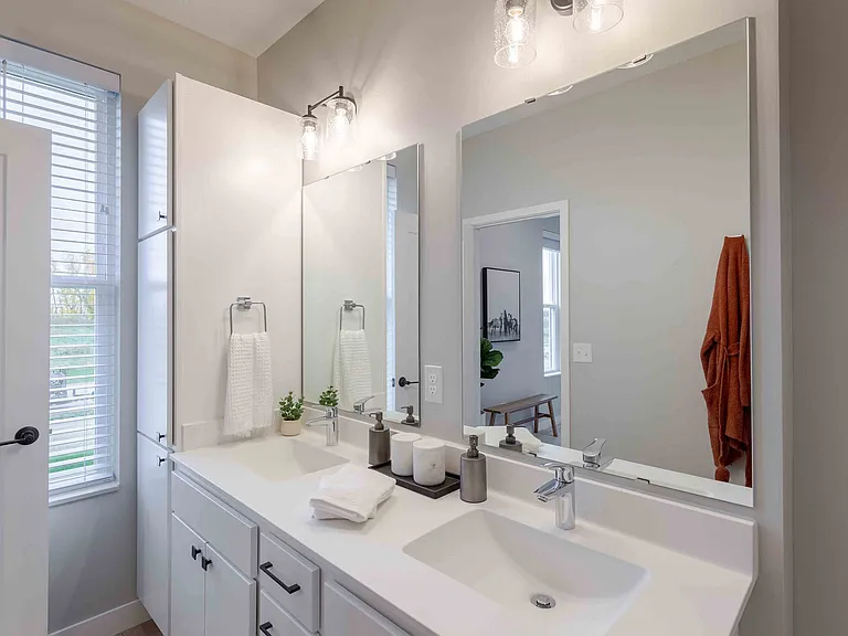 Contemporary bathroom with dual sinks, elegant lighting, and a large mirror enhancing the space.