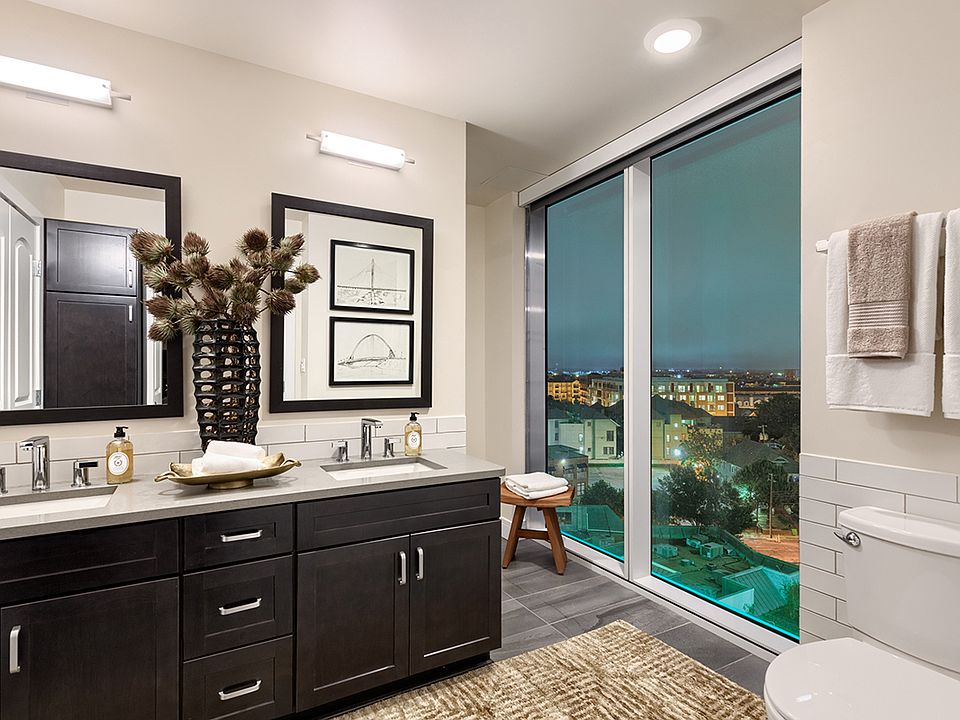 Luxurious bathrooms with large windows, dark cabinetry and framed mirrors