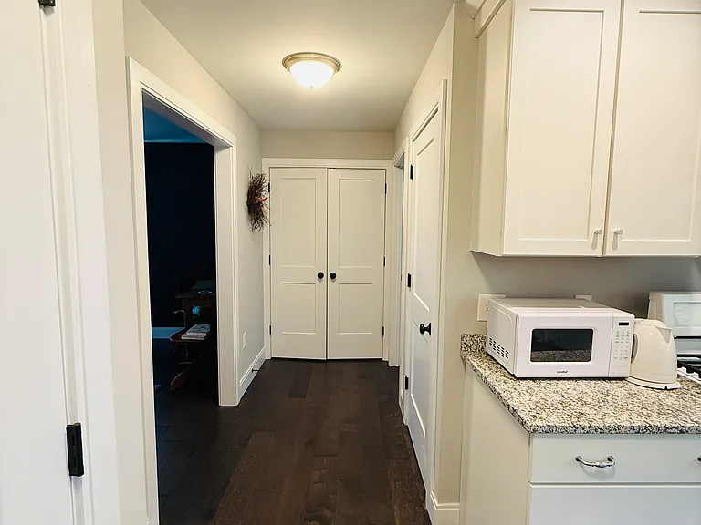 Kitchen hallway. Powder bathroom to the back right. Dining room and office space to the back left.