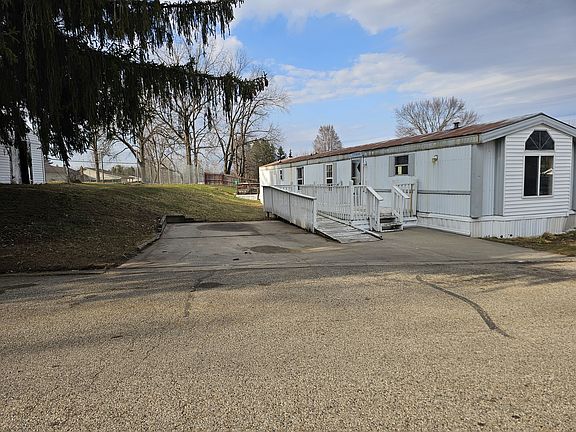 EXTERIOR OF HOME. LARGE PORCH WITH WHEELCHAIR ACCESSIBLE RAMP, LARGE DRIVEWAY FOR OFF-STREET PARKING, LARGE LOT WITH STORAGE SHED.