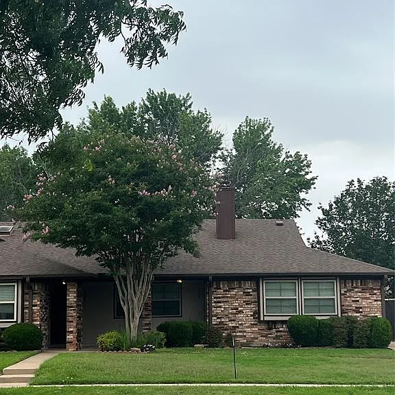 Brick exterior featuring a gabled roof with landscaping