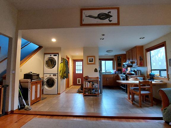 This photo is a good overview of the kitchen from the living room, but it contains things that don't come with the house: the gate, the shelving in the center, the personal belongings and framed photos/ pictures.