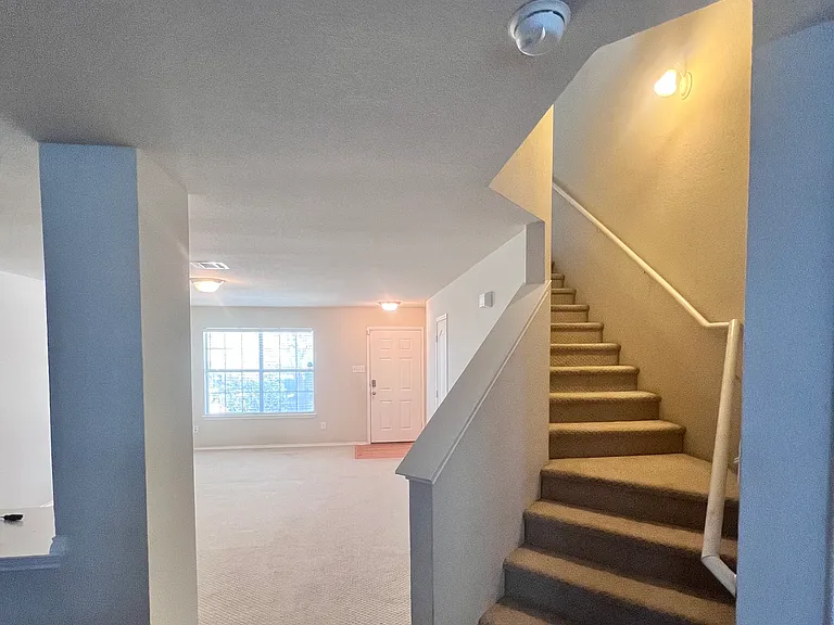 Front entryway into kitchen with shot of staircase/bar.