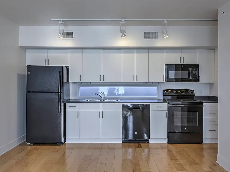 Kitchen with white cabinets and black appliances at The Sawyer.