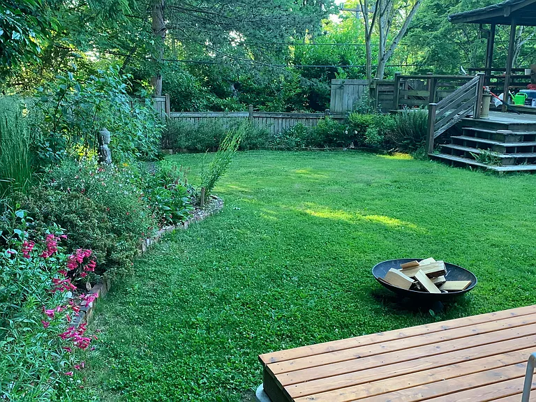 Private fully-fenced back yard with mature plants and landscape lighting.