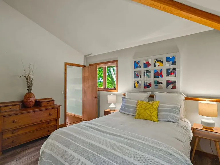 This inviting bedroom boasts high ceilings, warm wood accents, and natural light for a peaceful retreat.