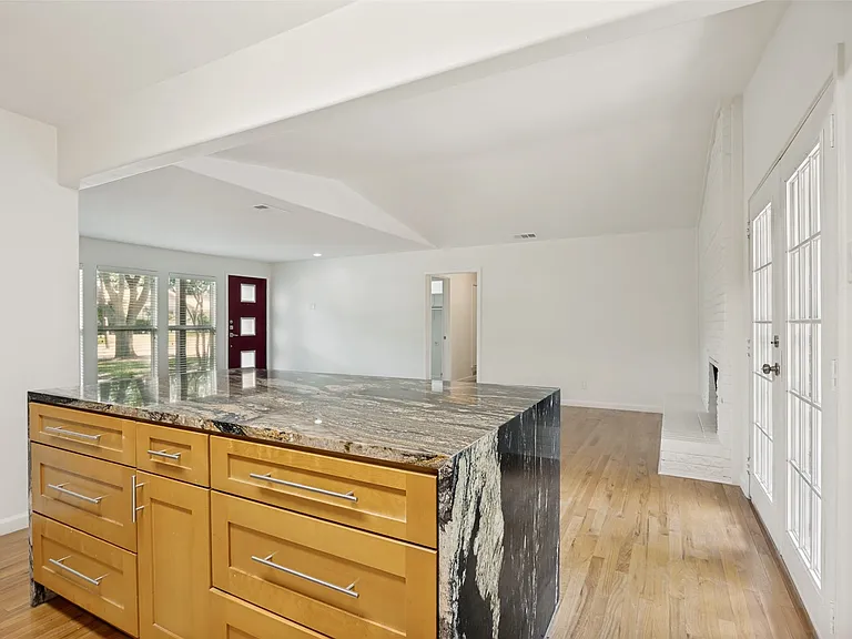 Kitchen island featuring wood cabinetry with stainless steel pulls and a granite countertop