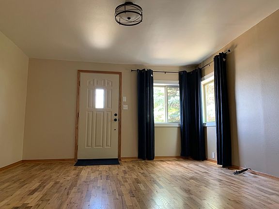 Living room. Updates done in 2022: Refinished hardwood flooring, paint, light fixture, and curtains. The main level receives plenty of natural light.