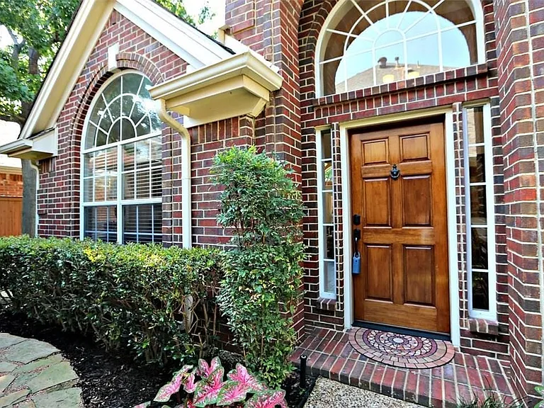 Brick facade featuring a warm wood-panel entry door, arched transom window, and sidelight windows