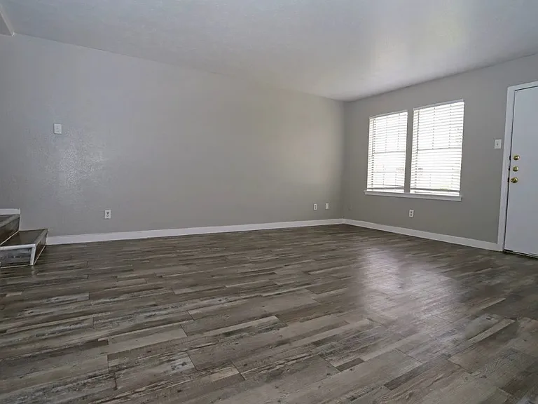 Open-concept living area with wood-style flooring and natural light throughout.