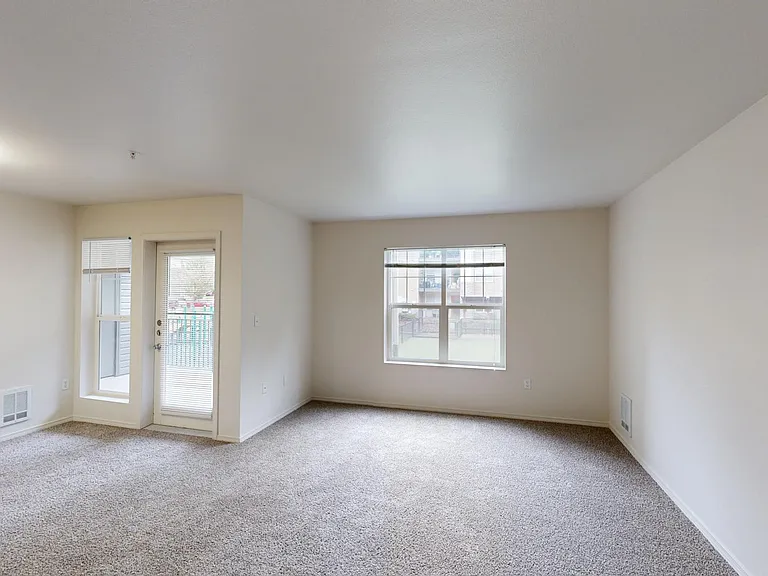 Apartment living room with plush carpet flooring.