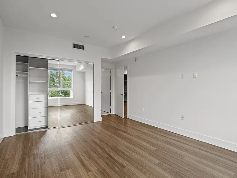 Bedroom with Mirrored Closet with Built-In Shelving, Recessed Lighting, and Vinyl Flooring