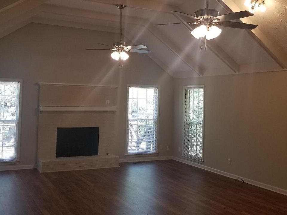 Living room with wood fireplace and high rafter ceiling.