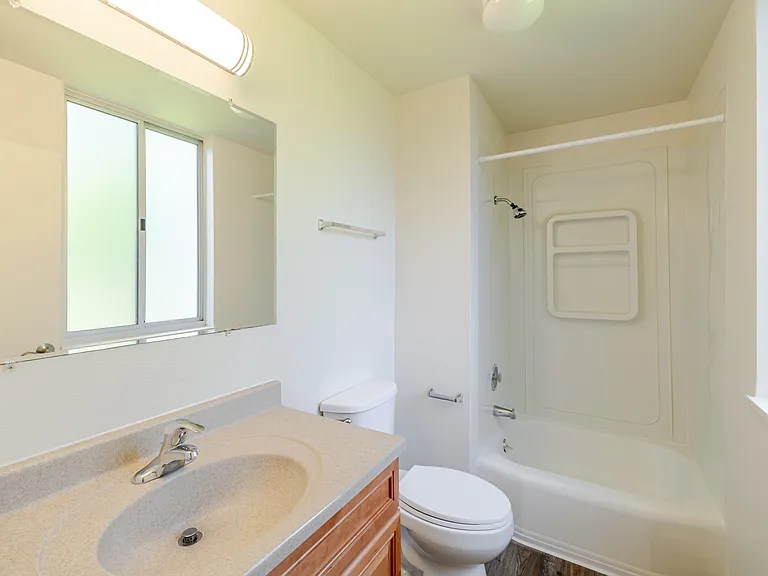 Bathroom B is complete with a large mirror, full bathtub, and convenient natural light from a frosted window.