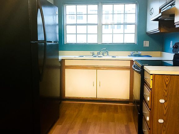 Kitchen view from spacious dining area, with updated lighting, new appliances, and large windows.