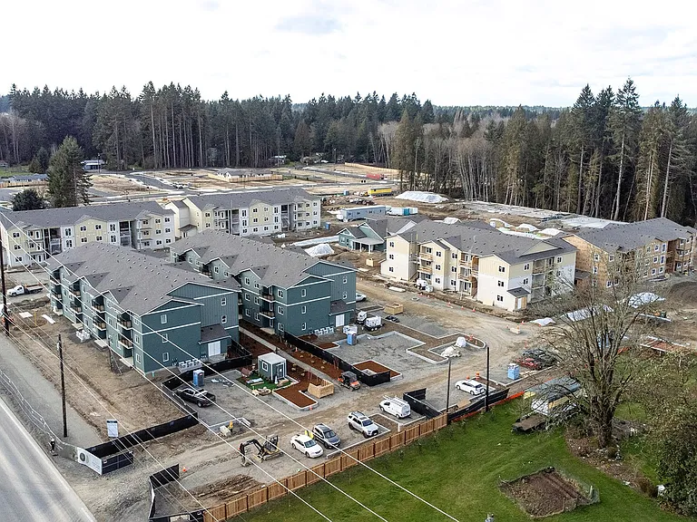 Early construction at The Elowen in Lacey WA. New apartment homes emerging among the towering evergreen trees on an overcast Pacific Northwest day.