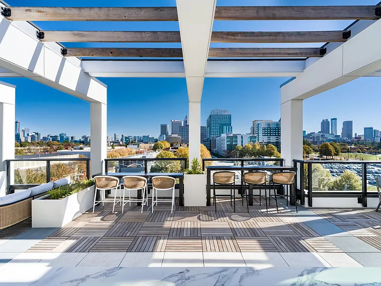 Pergola-covered rooftop seating at Modera Westside Trail with skyline views, bar-height tables, and open-air areas designed for gathering or downtime.