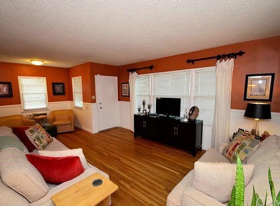 Living room with picture window facing east, hardwood floors and reading nook or extra dining area.