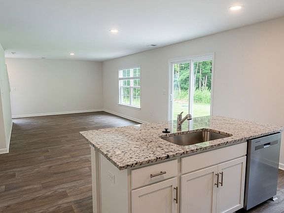 Stainless dishwasher is built-in on the side. Open sightlines continue into the living area and backyard beyond.