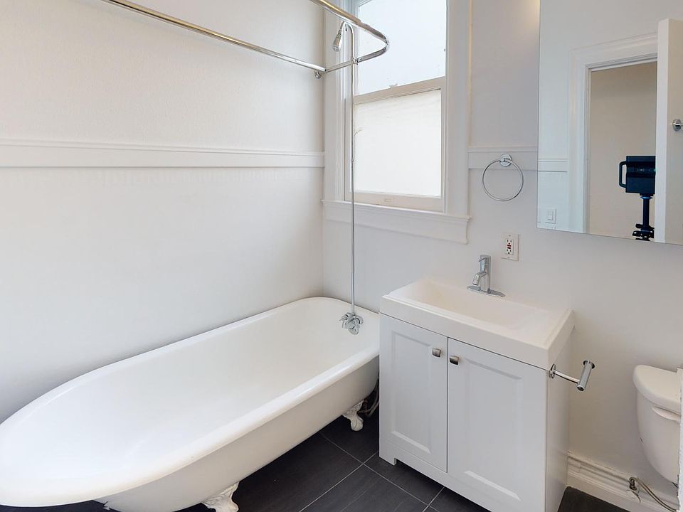 Bathroom featuring a clawfoot tub, sleek sink cabinet, mirror, natural light streams in