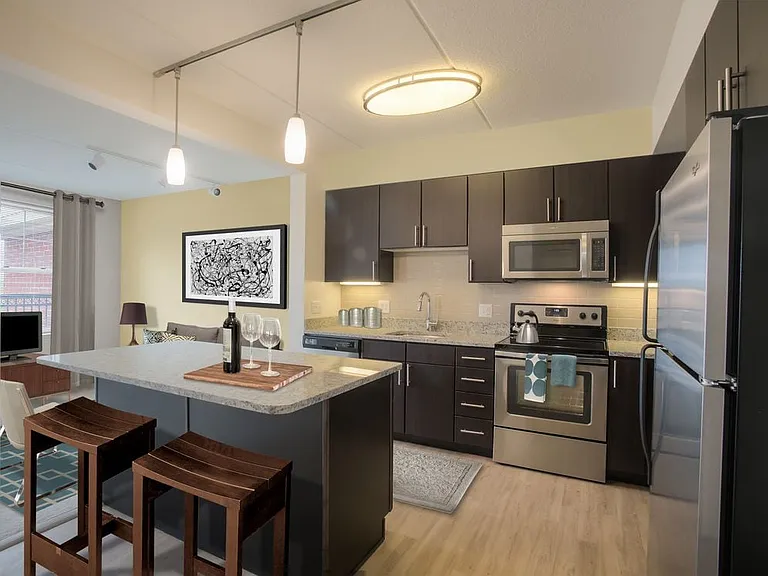 Classic Package kitchen with grey granite countertops, espresso cabinetry, stainless steel appliances, tile backsplash, and hard surface flooring throughout (in select homes)