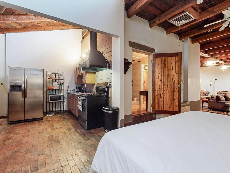 Bedroom with views of the kitchen, bathroom door entrance, and living room area.