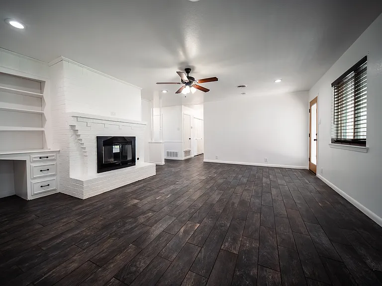 Open living room with fireplace, ceiling fan, and beautiful hardwood flooring