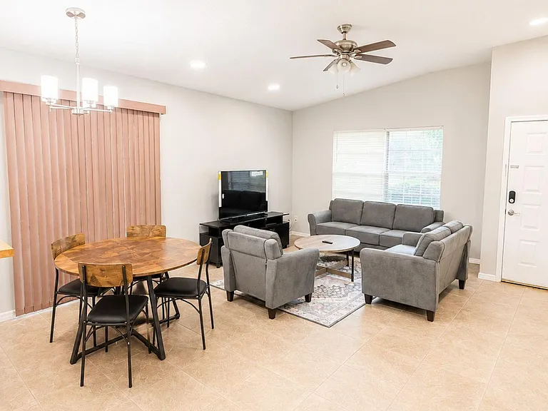 Open living and dining area with comfortable seating, TV setup, ceiling fan, and easy-care tile flooring.