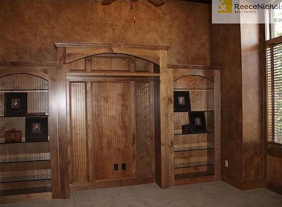 A main level private home office has a high ceiling, a full wall of shelving and French doors.