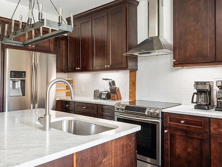 Fully stocked kitchen with dishware and appliances. Features marble countertops, new leather bar chairs, custom lighting and stylish wooden accent wall.