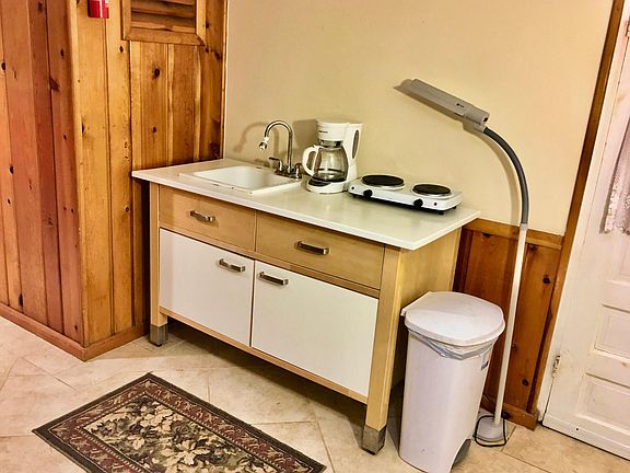 Kitchenette features sink with disposal, dishes, cups and silverware.