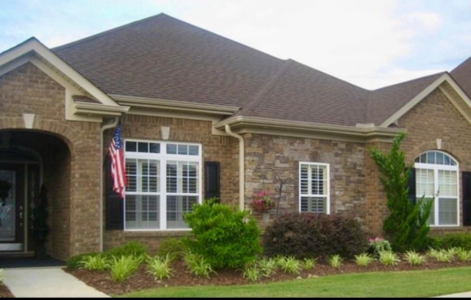 Front of house with covered entranceway and eave lights. Street is lined on both sides with trees. Sidewalks for walking throughout community.