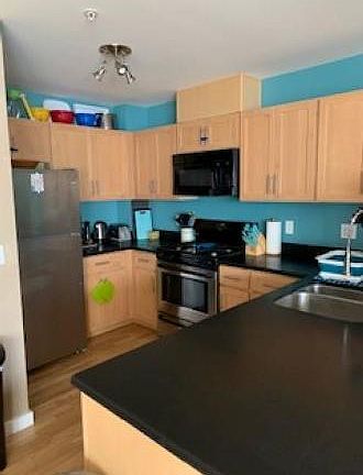 Open kitchen with black quartz countertops + gas stove w/ 4 burners + full sized refrigerator