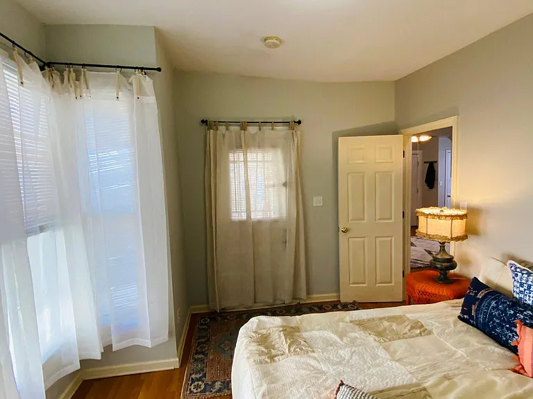 The view from the First bathroom shows the First bedroom's doors and Bay windows. One door opens to the covered side porch and the other to the hallway.