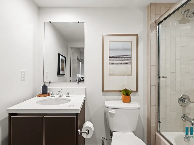 Bathroom with Full-Size Bathtub with Glass Door and Cabinet Storage