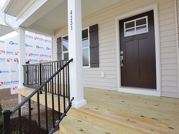 A newly constructed front porch in Poplar Village, Lot 31, features wooden steps and a dark brown do