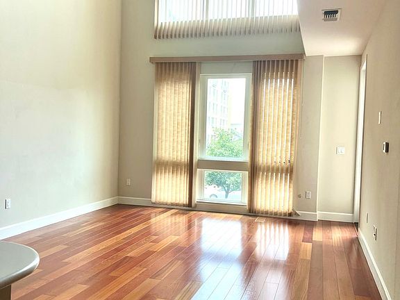 Well lit ample living area with hardwood floor.