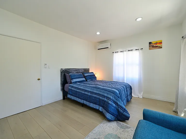 Super spacious bedroom furnished with TV, queen bed and mattress, mini split AC, Loveseat and Coffee table - with views of PCC