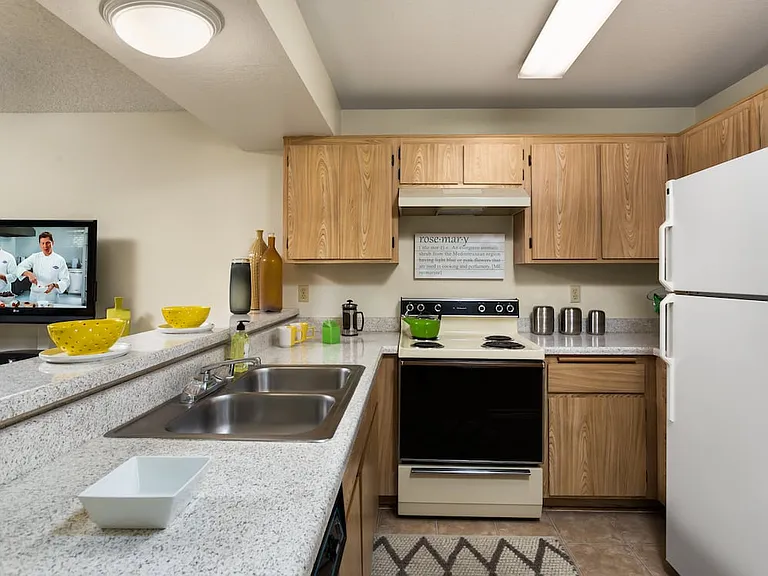 Classic Package kitchen with white appliances, oak cabinetry, white speckled granite countertops, and tile flooring