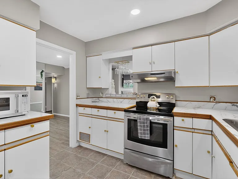 Bright kitchen with white cabinetry and sleek stainless steel appliances.