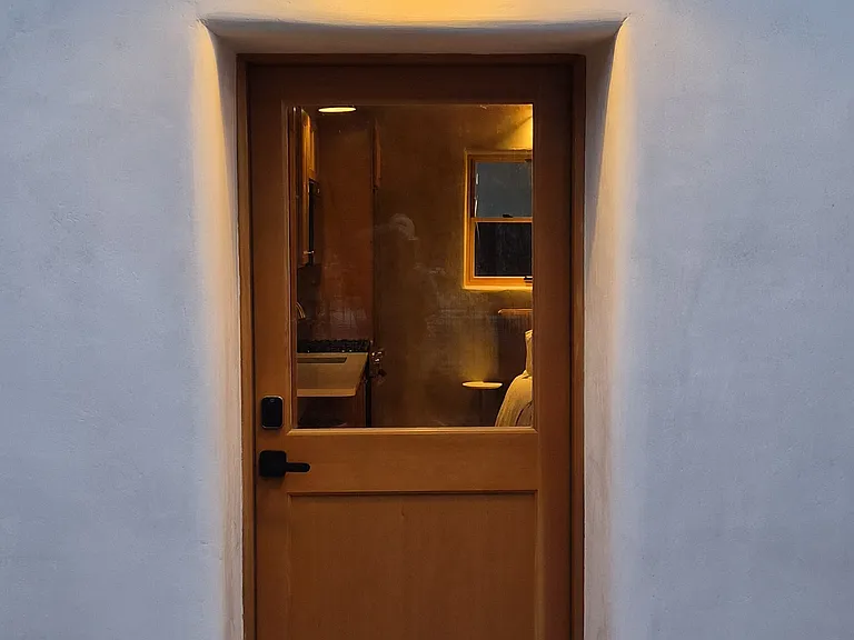 entry door, smooth lime stucco and stepped adobe parapet