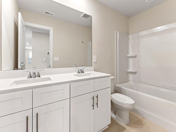This secondary bathroom features dual-sinks and an oversized shower tub.