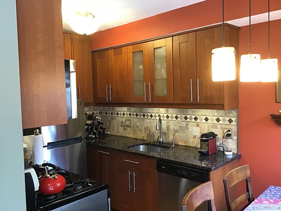 Galley kitchen with stainless steel appliances, granite counters and Italian stone backsplash. Under cabinet lights and lights inside the cabinet with a glass door. Built-in microwave oven.