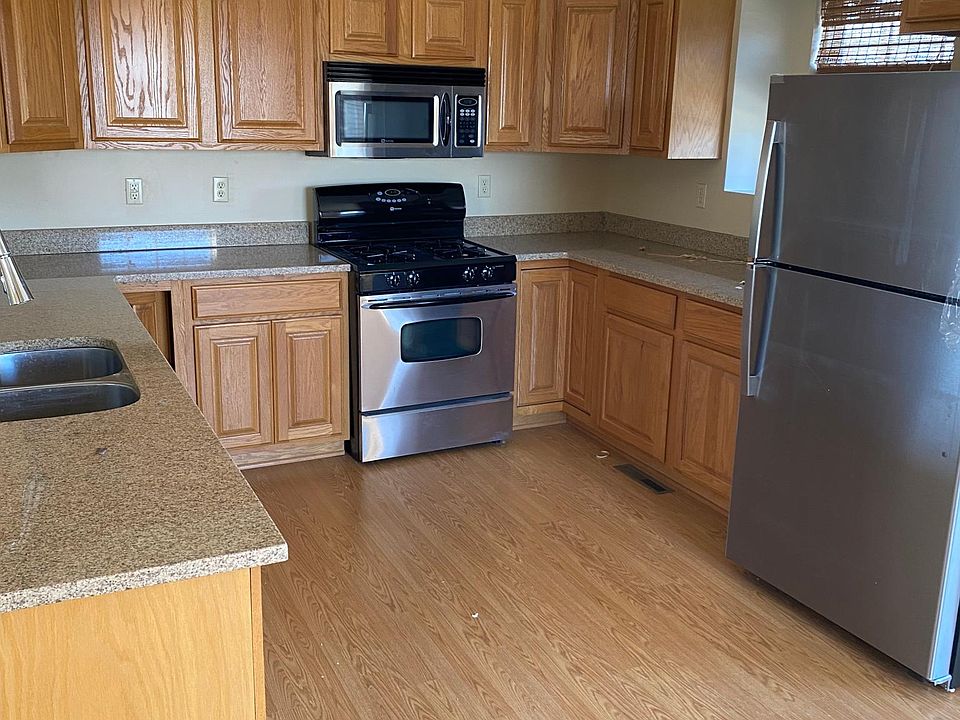 Kitchen with Stove, Microwave, Refrigerator and hard surface counter top.