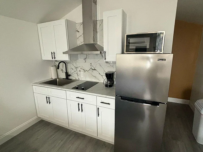 Kitchen with refrigerator, coffee maker, microwave, cabinets, and essential amenities.