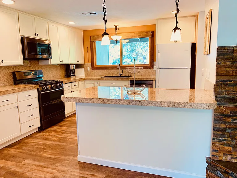 The large, open kitchen is adjacent to the dining room and living room. Features include all appliances, instant hot water at the sink, an island, and tile counters.